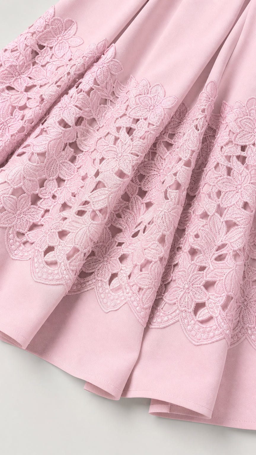 Close-up of intricate cutwork embroidery hem on pink dress