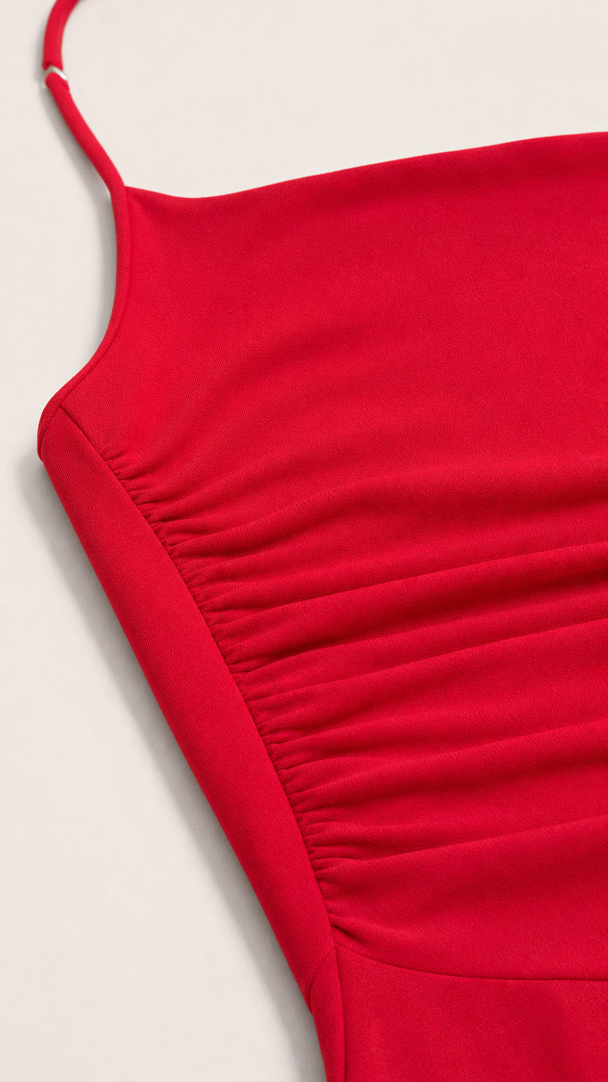Close-up detail of fabric texture and side ruching on red dress