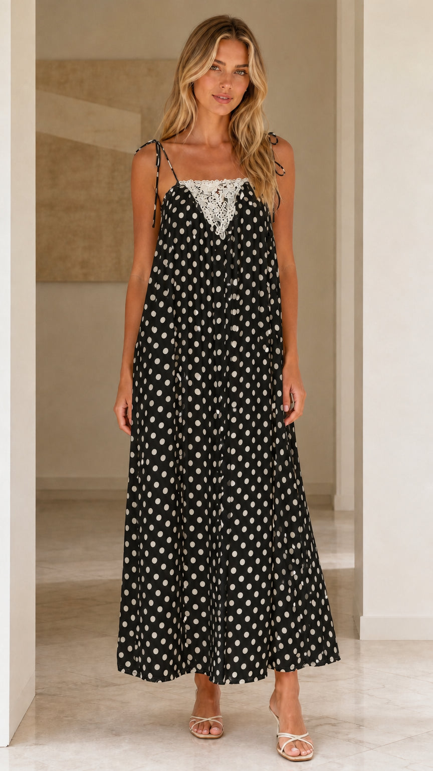 Front view of woman wearing black polka dot maxi dress