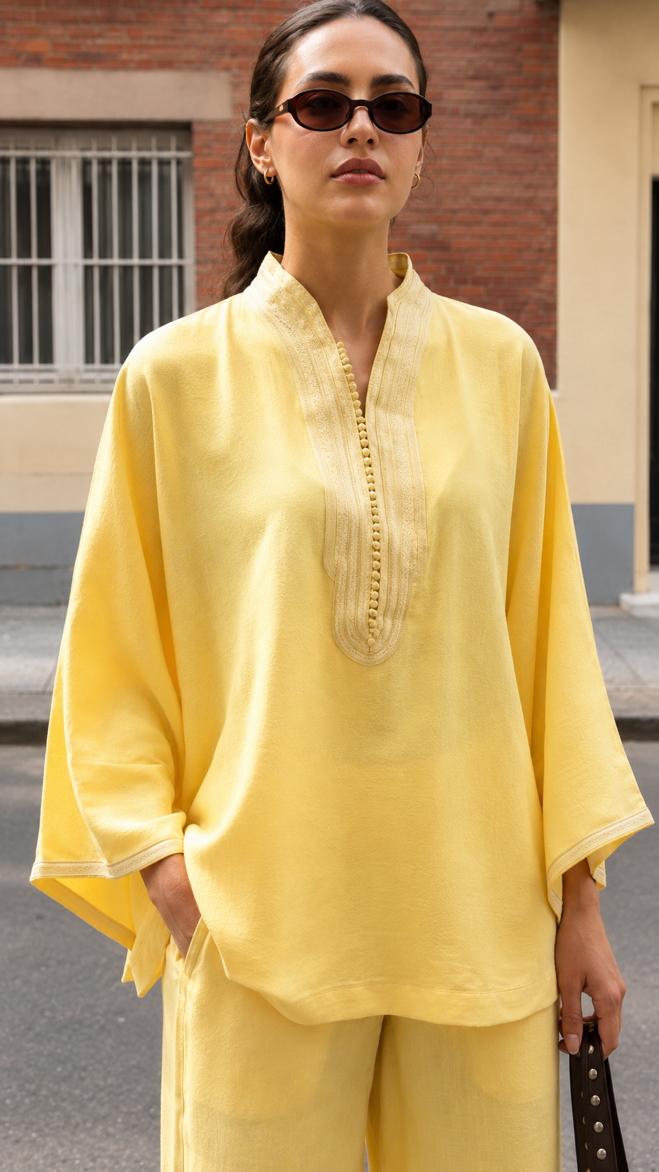 Close-up of butter yellow tunic showing embroidered split neckline and draped sleeve detail