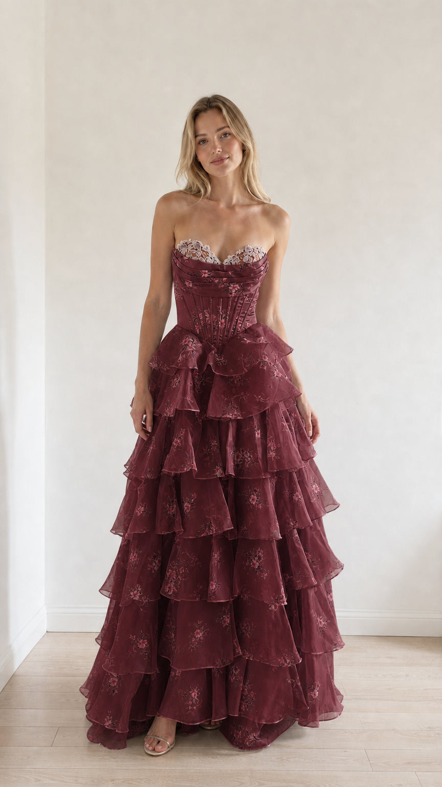 Model wearing burgundy floral tiered ruffle strapless evening gown